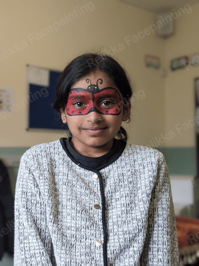 Child with a red and black ladybird mask face painting