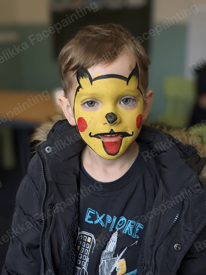 Child with a yellow cartoon creature face painting with rosy red cheeks