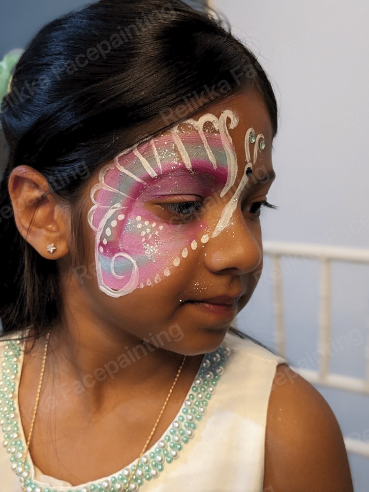 A child at a party with a pink and white butterfly face painting